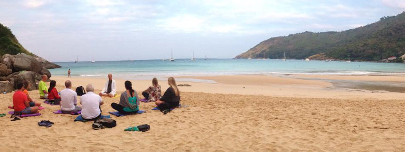 Ten people meditate together at Naiharn Beach in Phuket during a retreat.