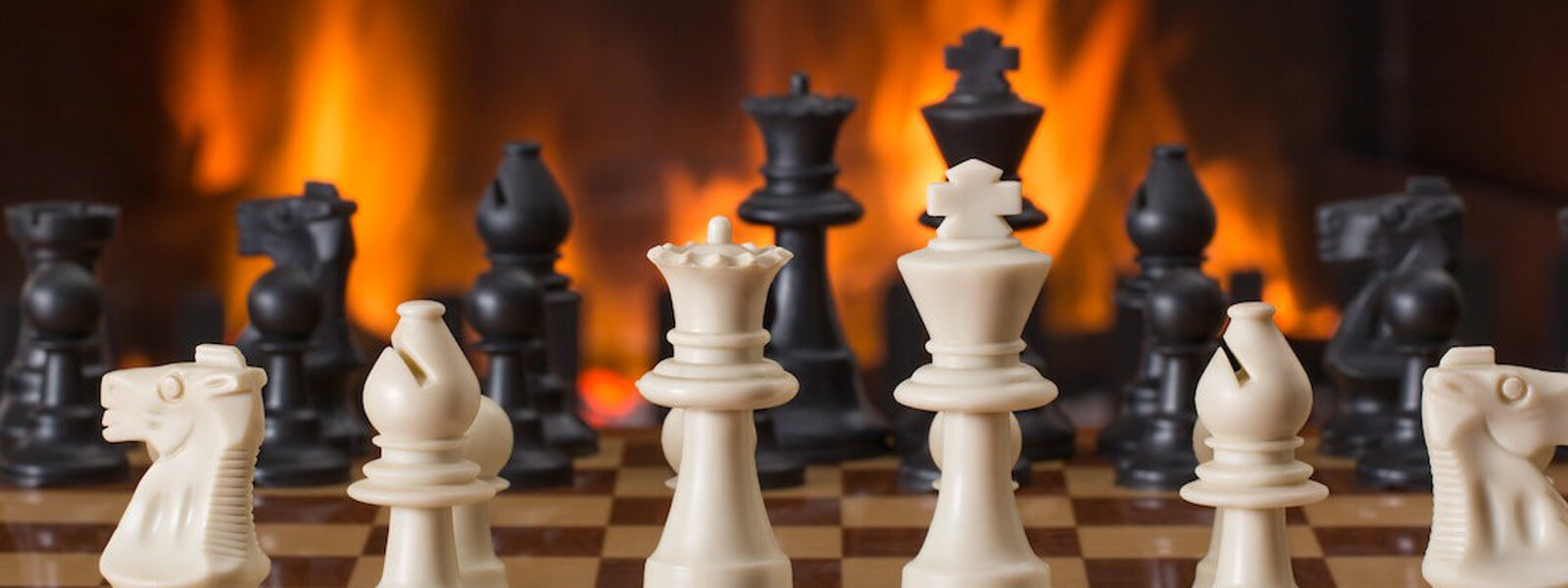 Close up of a chessboard. A fire is burning in the blurry background.