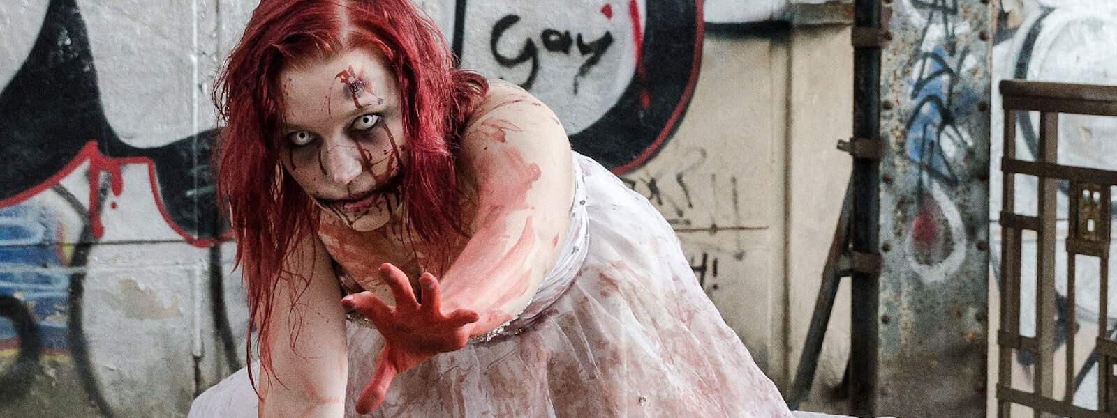 Red haired, bloody female Zombie in a wedding dress, reaching out.
