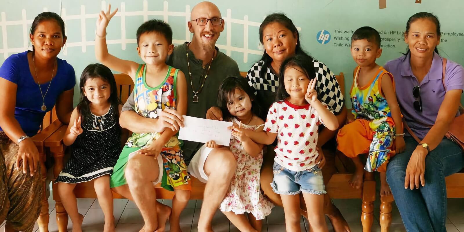 Tobi and Parn giving a Donation in an envelope to Childwatch Association in Phuket.
