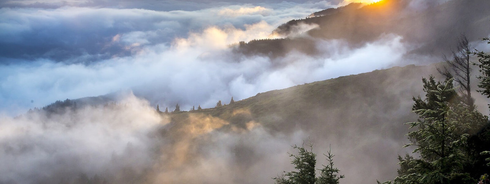 Clouds embracing the hills up in the mountains during sunrise.