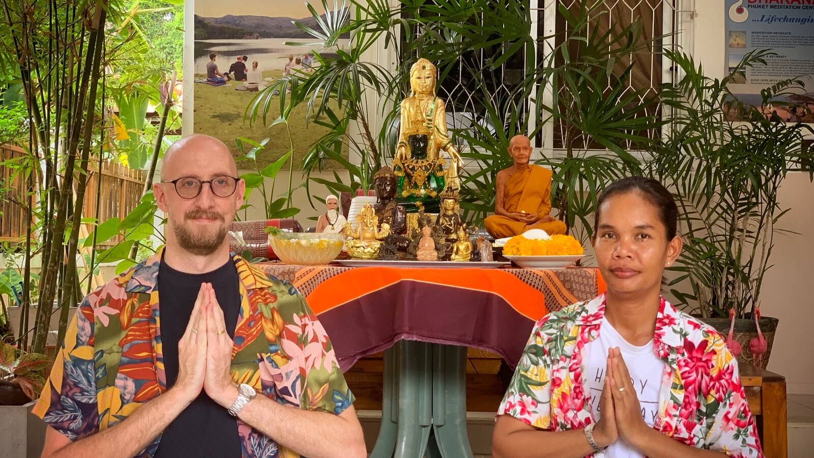 Tobi and Parn at the entrance of the Phuket Meditation Center. Behind them there is a table with Buddha statues.
